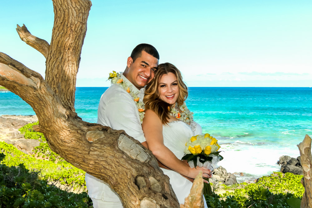 Couple leaning against a tree by the ocean